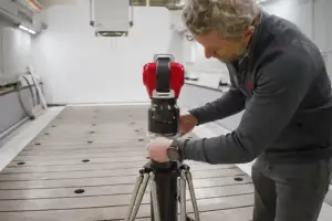 Person adjusting a red camera mounted on a tripod in a bright laboratory.