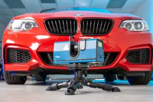 Red BMW car with a camera rig mounted on a stand beneath the front bumper.