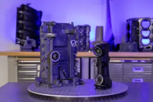 Blue-lit workshop with a circular platform holding a blue robotic frame and an articulated arm, with tools and components in the background.