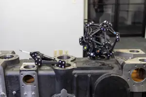 A black, jointed chain sculpture rests on a gray metal engine block.