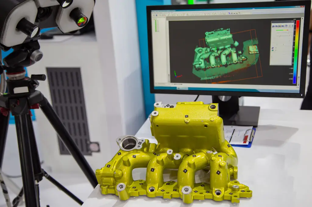 3D scanning of yellow engine intake manifold with structured light scanner and point cloud shown on computer monitor